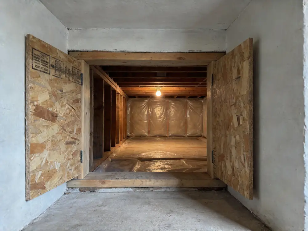 Open crawl space hatch with encapsulation sheeting visible inside