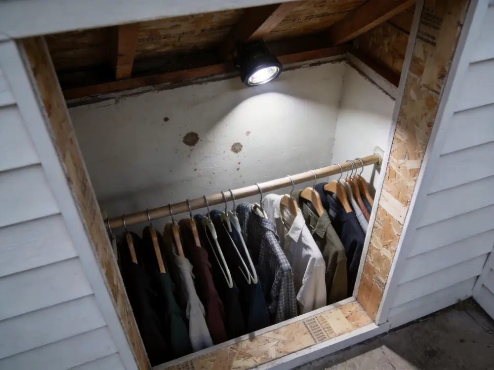 Clothing in a closet against a spotted exterior wall