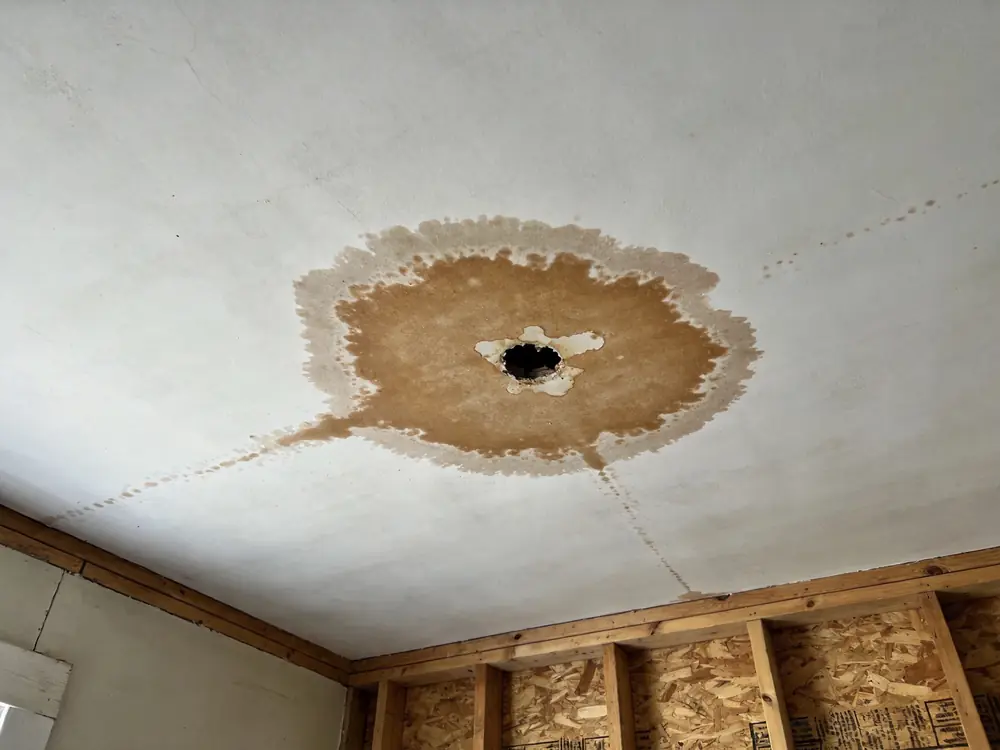 Brown water stain spreading across a ceiling below a leak