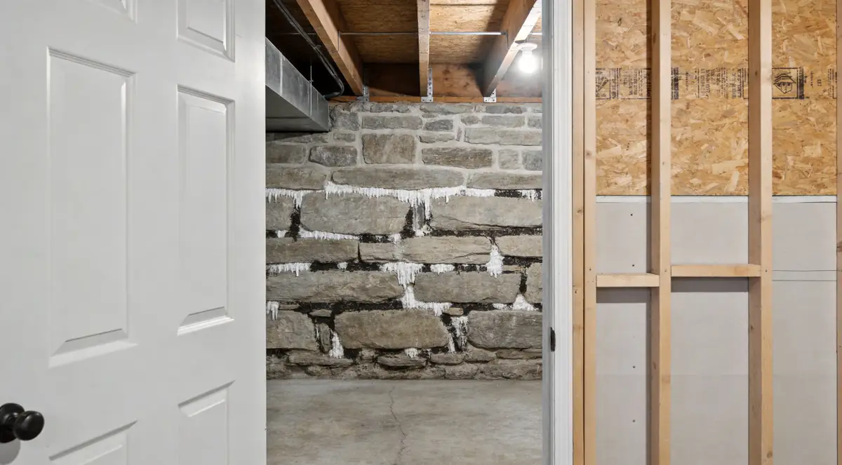 White mineral deposits and dark patches on a stone foundation wall
