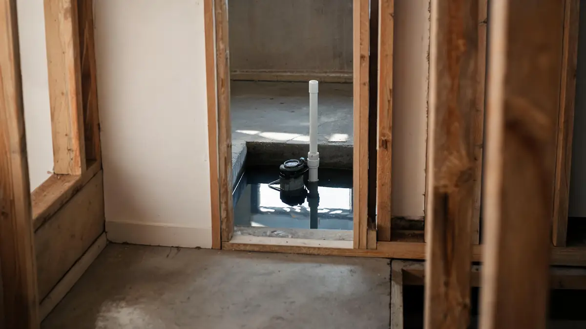 A sump pump sitting in a flooded basement pit