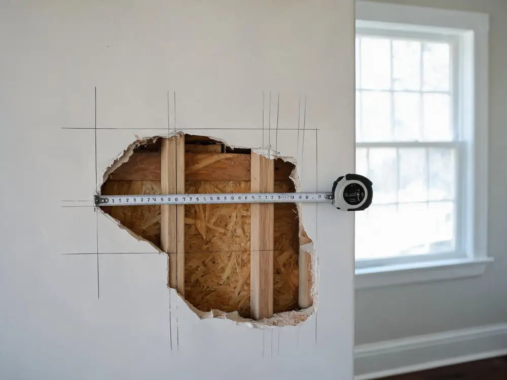 Tape measure pulled across a damaged wall section