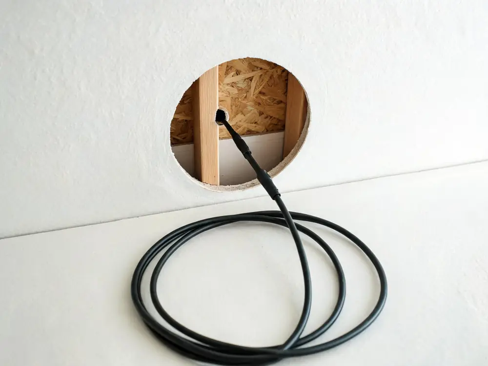 Borescope probe inserted through a small hole in drywall