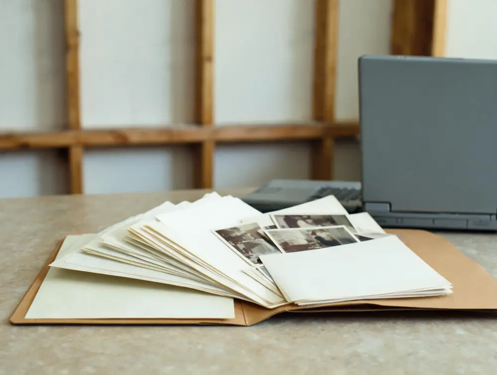 Folder of documents and photographs spread on a kitchen table